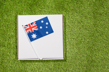 Paper box of pizza with Flag of Australia on the grass. Concept. Top view