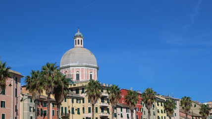 Fototapeta na wymiar Colorful buildings at the seafront road and the tower of the Catholic church in Genoa Pegli, Italy