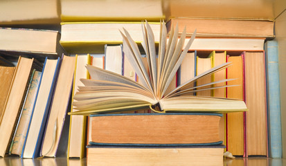 open book in front of a row of books in a book shelf. Reading, learning, education, literature...