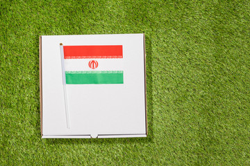 Paper box of pizza with iranian Flag on the grass. Concept. Top view