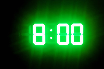 Green glowing digital clocks in the dark show 8:00 time