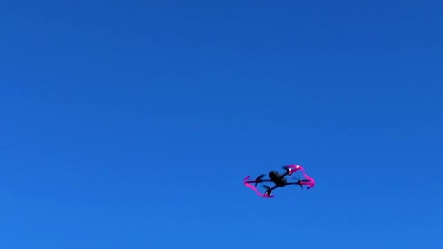 Drone performing a side flip stunt in the air with blue sky in the background