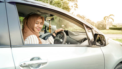 portrait of hijab women looking at the camera with a smile while sitting inside a car