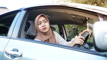 portrait of young Muslim hijab women while driving a car looking forward