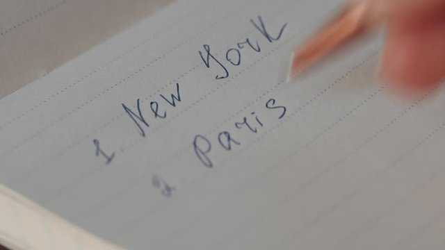 Woman writing city in a notebook close-up