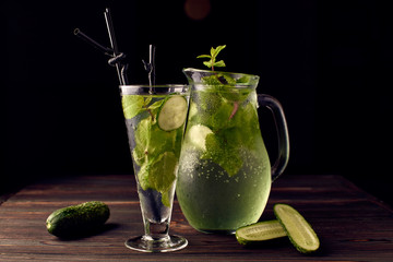 Lemonade a cucumber in a glass on a dark background