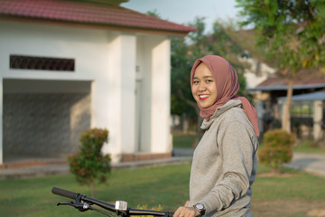 Fototapeta na wymiar portrait of a hijab woman outdoors with a bicycle posing in front of the camera. Wearing fashionable and casual jeans.