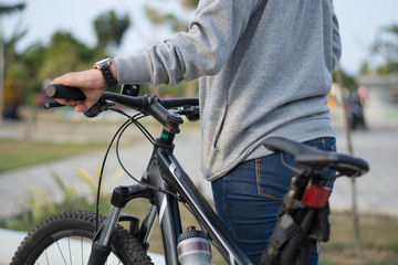 close up shot of hijab  woman's hand was holding the wheel of a bicycle from behind in a park