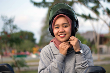 portrait of hijab  woman wearing a helmet before riding a motorcycle in a park