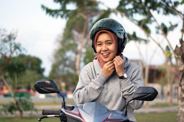 portrait of hijab  woman wearing a helmet before riding a motorcycle in a park