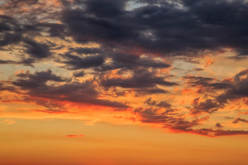 Heavenly summer background. Beautiful bright majestic dramatic evening sky at sunset or sunrise orange and blue with rays. The sun shines over the horizon against the backdrop of thunder clouds