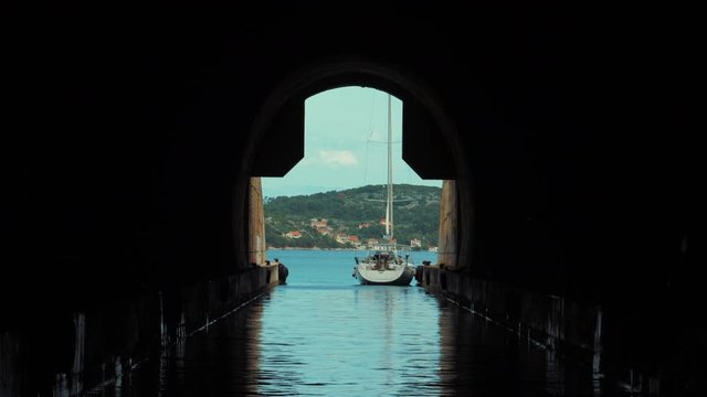 Beautiful shoot from the inside of the submarine/military tunnel. A white sailboat is parked outside on a summer day. Travel holiday destination. 