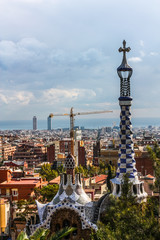 Overview of the Right Pavilion with a Pinnacle, crowned with a Gaudi-typical five-beam cross of the Park Guell in Barcelona, Spain