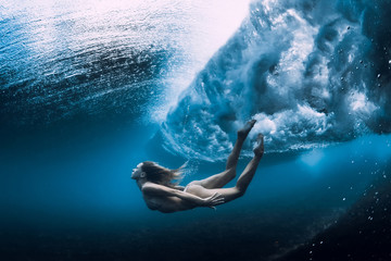 Woman swim underwater with ocean wave.
