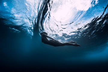 Slim woman dive underwater with under barrel wave