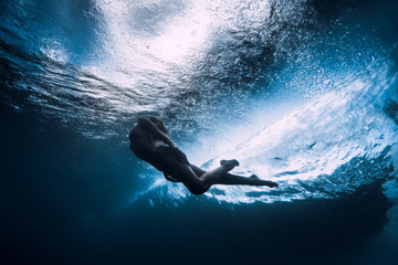Woman dive underwater with ocean wave.