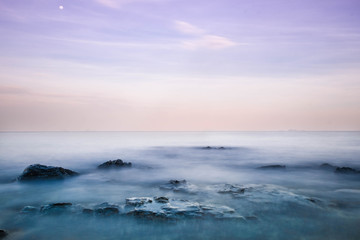 Long exposure of the waves that cover the rocks in the sea and the beautiful colors of the sky in dusk looks like a dream.