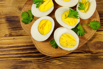 Boiled eggs with parsley on cutting board on a wooden table. Top view