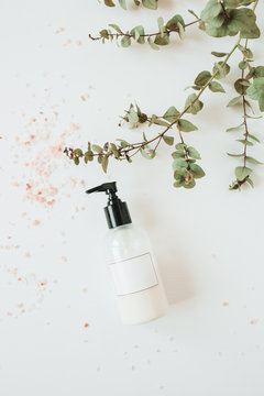 Skin care spa concept with blank mockup cream / liquid soap bottle, eucalyptus on white background. Flat lay, top view beauty lifestyle cosmetics composition.