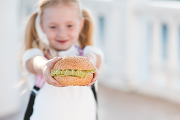 Girl holding fresh hamburger with lettuce closeup. Fast food. Junk food. Back to school. Good...