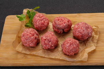 Raw meatball over wooden background