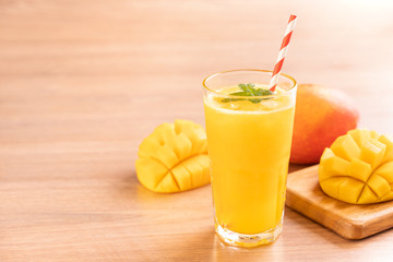 Fresh mango juice with beautiful chopped pulp flesh and straw on bright wooden table background. Tropical fruit design concept. Close up, copy space.