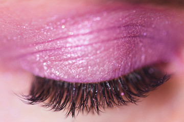 Beautiful false eyelashes and pink eyes shadow on closed eyelid closeup. Selective focus.