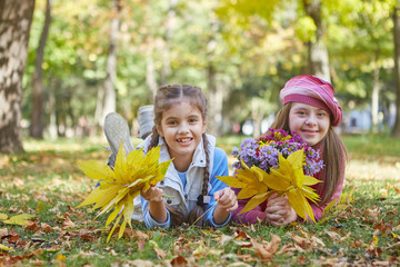 Girl with Down syndrome and little girl in autumn park.