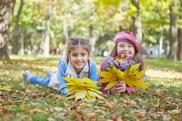 Girl with Down syndrome and little girl in autumn park.