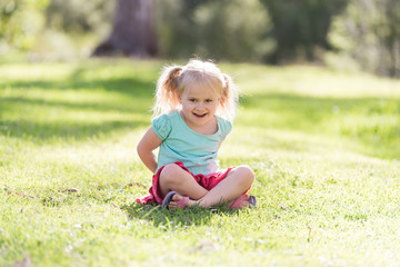 little girl sitting on the grass smiling