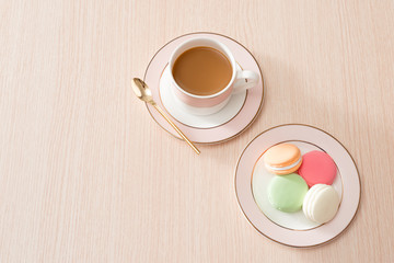 Cup of coffee with macaroons on wooden background
