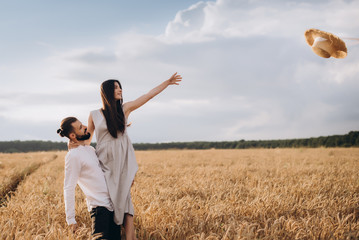 Outdoor shot of young couple walking through meadow hand in hand. Man and woman talking walk through Wheat Field in countryside. selective focus