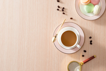 Obraz na płótnie Canvas Cup of coffee with macaroons and coffee beans on wooden background