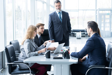 Mature businessman talking and explaining his business strategy to his colleagues at office.