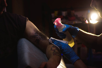 Tattoo artist makes a tattoo on a man's hand.
