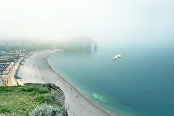 Misty morning fog at the famous natural cliffs in Etretat. Etretat is a commune in Seine-Maritime department in Haute-Normandie region in France. Etretat is now a famous French seaside resort