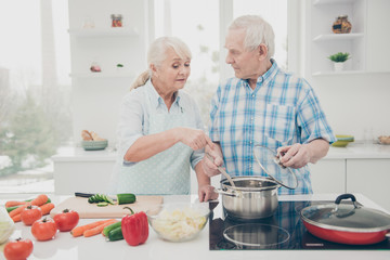 Portrait of his he her she nice attractive concentrated focused careful helpful spouses cooking fresh delicious new domestic dishes pasta soup in modern light white interior kitchen indoors