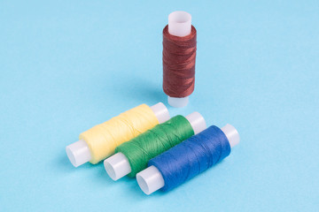 colored spools of sewing thread on a blue background
