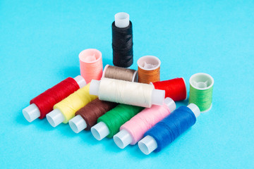 colored spools of sewing thread on a blue background