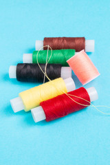 colored spools of sewing thread on a blue background