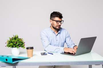 Young manager working on laptop sitting at desk in bright office