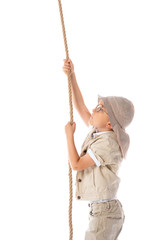 side view of focused explorer kid in hat and glasses holding rope isolated on white