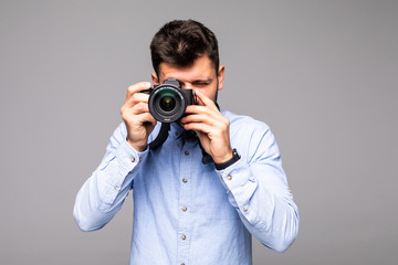 Obraz premium Young man take photo with dslr camera looking at camera isolated over gray abackground.