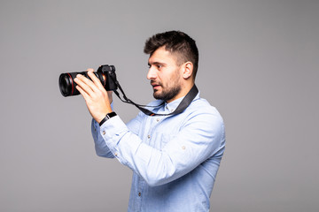 Young man take photo with dslr camera looking at camera isolated over gray abackground.