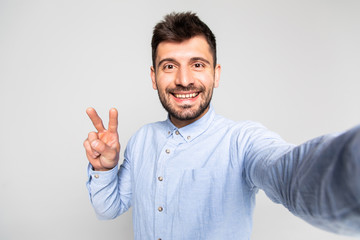 Naklejka premium Close up portrait of satisfied handsome careless restless with beaming toothy smile blogger isolated on gray background copy-space