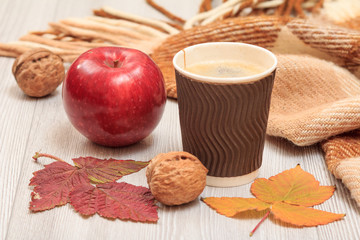 Cup of coffee, walnut, apple and dry leaves in an autumn still llife.