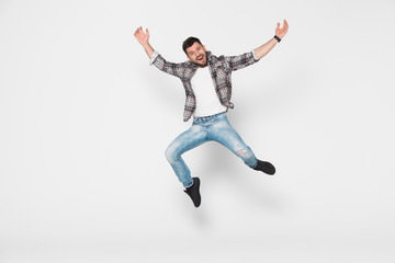 Fototapeta na wymiar Happy man in shirt and jeans which jumping in studio over white background