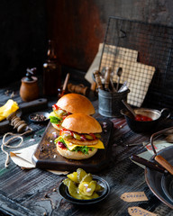 two homemade burgers with fried chicken, lettuce, cheese, onion, pickled cucumbers, ketchup