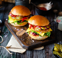 two homemade burgers with fried chicken, lettuce, cheese, onion, pickled cucumbers, ketchup