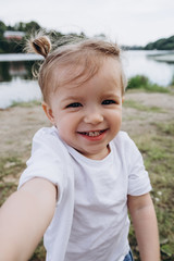 a portrait of a little smiling baby girl who stretches her hands to someone to hug and kiss, the emotion of happiness, joy, funny childhood